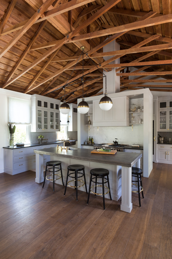 Open concept kitchen - transitional u-shaped medium tone wood floor open concept kitchen idea in San Francisco with an undermount sink, glass-front cabinets, white cabinets, gray backsplash, ceramic backsplash, stainless steel appliances and two islands