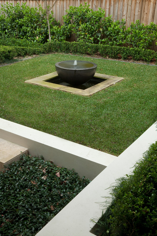Small traditional backyard partial sun formal garden in Sydney with a water feature and natural stone pavers for winter.