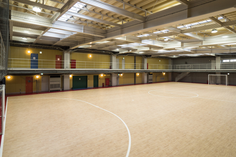Expansive scandinavian indoor sport court in Tokyo with yellow walls and exposed beam.
