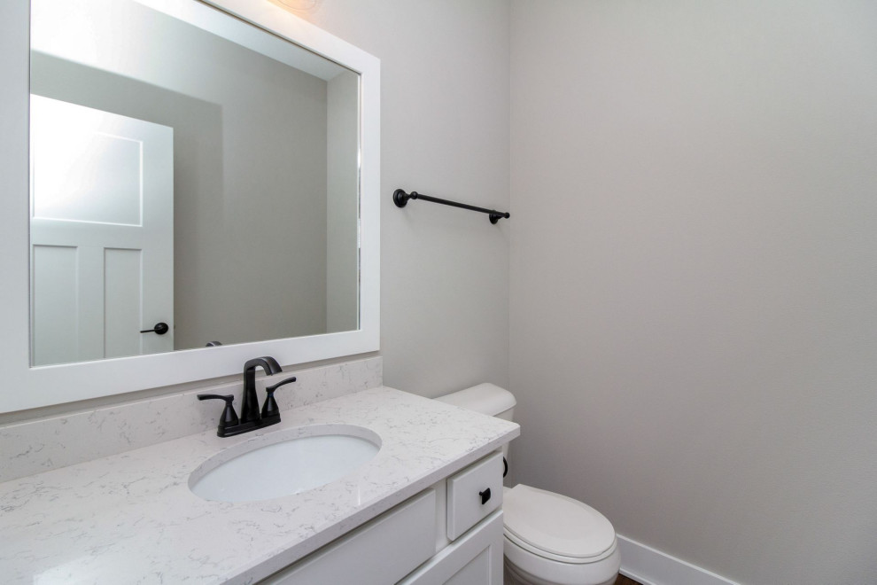 Example of a small transitional ceramic tile and gray floor bathroom design with shaker cabinets, white cabinets, a two-piece toilet, gray walls, an undermount sink, quartz countertops and white countertops
