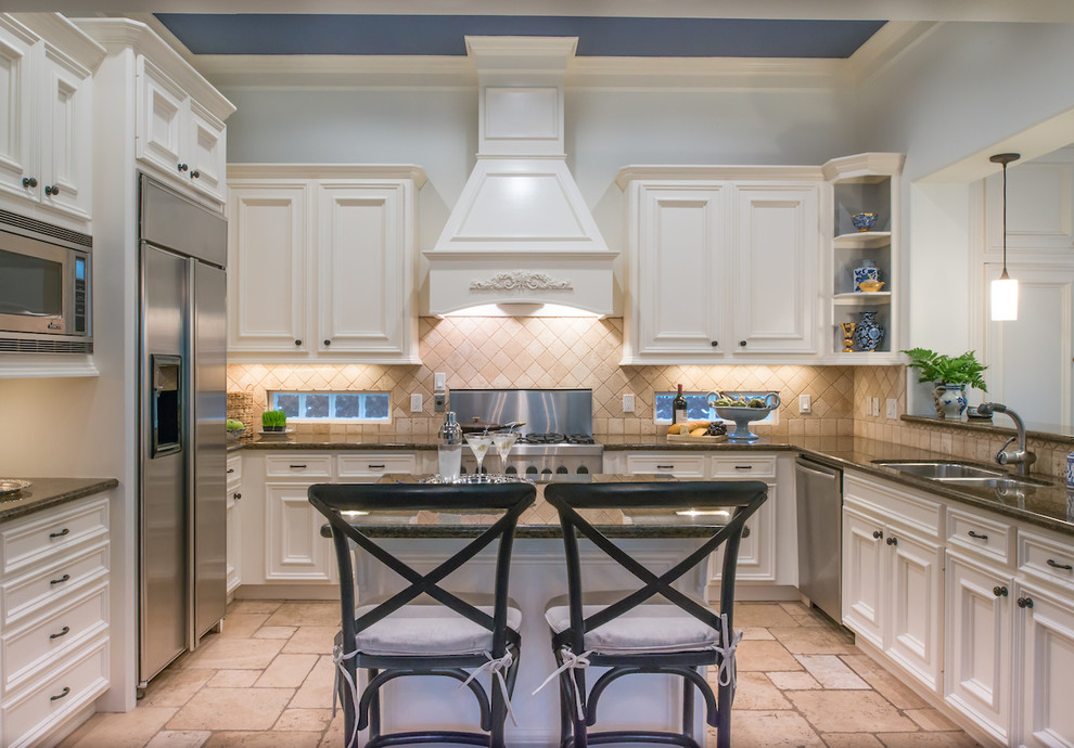 This is an example of a mid-sized traditional u-shaped eat-in kitchen in Austin with an undermount sink, white cabinets, granite benchtops, stainless steel appliances, with island, recessed-panel cabinets and white splashback.