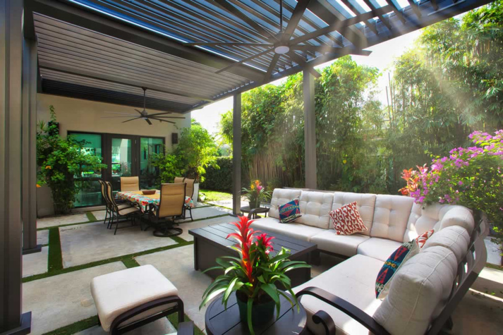 Esempio di un patio o portico tropicale di medie dimensioni e dietro casa con pavimentazioni in cemento e una pergola