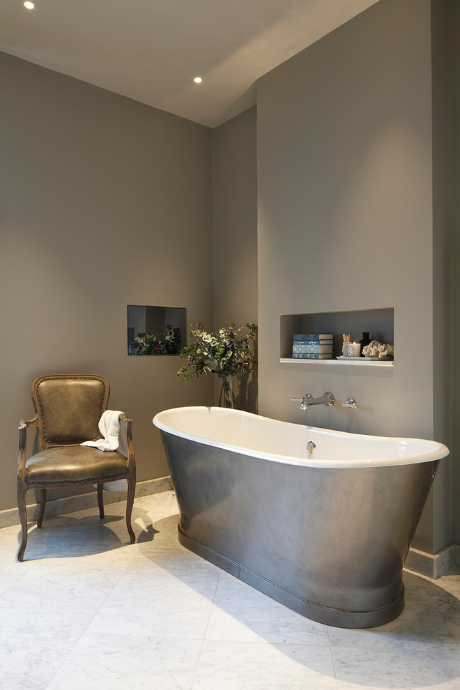 This is an example of a transitional bathroom in London with a freestanding tub and grey walls.