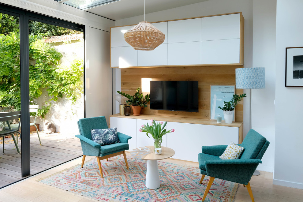 Photo of a mid-sized scandinavian open concept family room in Paris with white walls, light hardwood floors, a wall-mounted tv and beige floor.