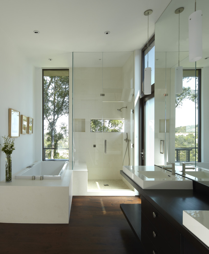 Inspiration for a mid-sized contemporary master bathroom in Los Angeles with a vessel sink, flat-panel cabinets, dark wood cabinets, a drop-in tub, a corner shower, beige tile, dark hardwood floors, wood benchtops, stone tile, white walls and black benchtops.