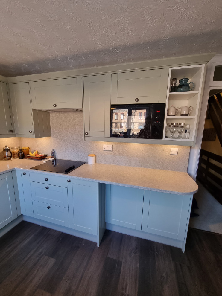 This is an example of a large traditional u-shaped separate kitchen in London with a double-bowl sink, shaker cabinets, white cabinets, quartzite benchtops, multi-coloured splashback, engineered quartz splashback, panelled appliances, linoleum floors, black floor and multi-coloured benchtop.