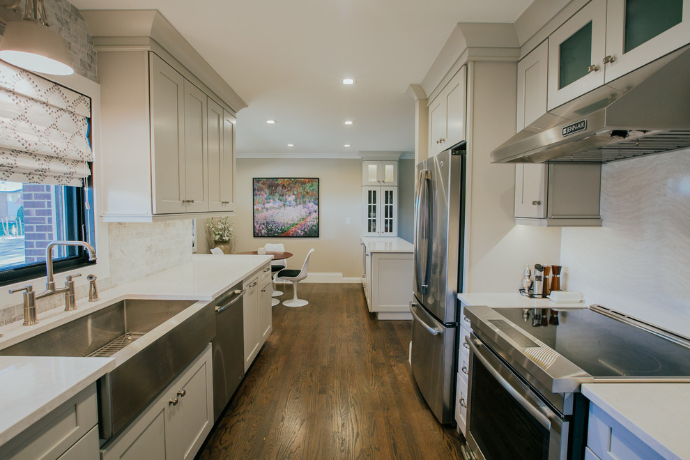 Inspiration for a large transitional galley separate kitchen in Denver with a farmhouse sink, shaker cabinets, grey cabinets, quartz benchtops, white splashback, marble splashback, stainless steel appliances, medium hardwood floors, a peninsula, brown floor and white benchtop.