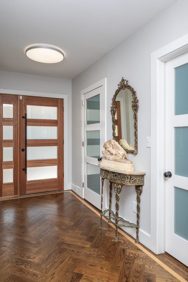 Large minimalist medium tone wood floor and brown floor entryway photo in Raleigh with white walls and a medium wood front door