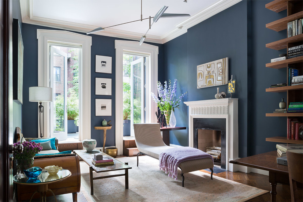Inspiration for a large transitional open concept living room in New York with a library, blue walls, a standard fireplace, medium hardwood floors and no tv.
