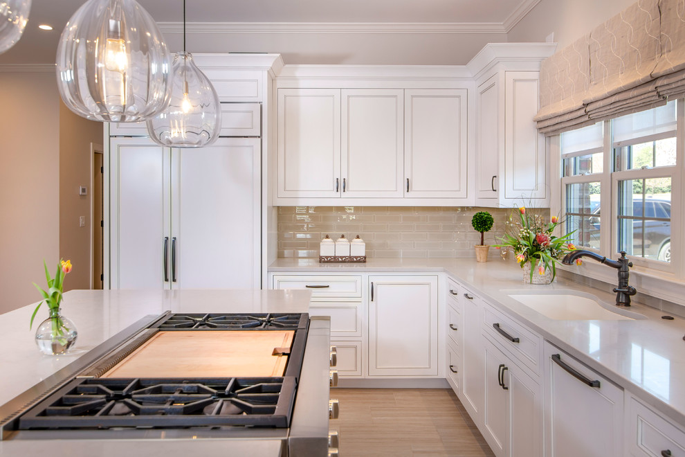 This is an example of a large transitional l-shaped kitchen in Charlotte with beaded inset cabinets, white cabinets, solid surface benchtops, beige splashback, glass tile splashback, with island, beige floor, an undermount sink, white appliances and beige benchtop.