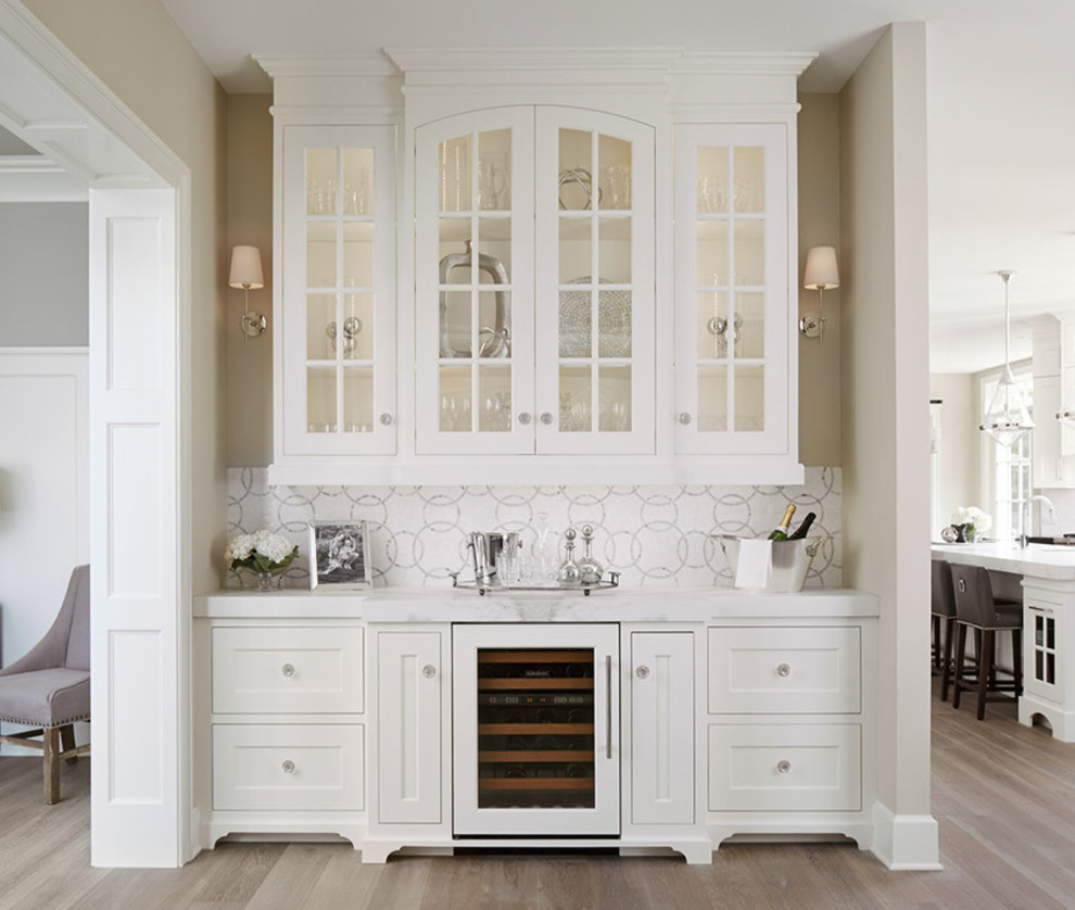 Traditional home bar in Chicago with no sink, glass-front cabinets, white cabinets, multi-coloured splashback, medium hardwood floors and white benchtop.