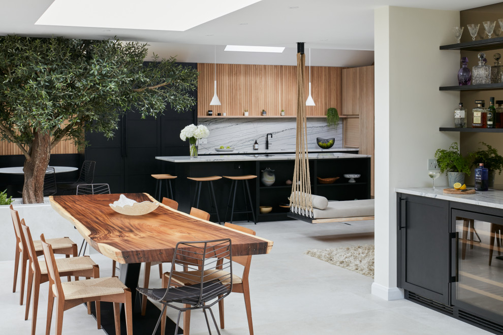 Large scandinavian open plan kitchen in London with a drop-in sink, flat-panel cabinets, black cabinets, quartzite benchtops, multi-coloured splashback, black appliances, with island and multi-coloured benchtop.