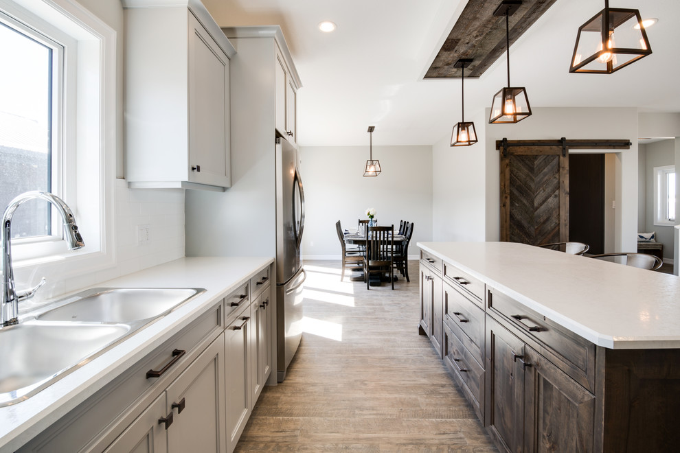 Large transitional l-shaped open concept kitchen photo with shaker cabinets, gray cabinets, laminate countertops, stainless steel appliances and an island