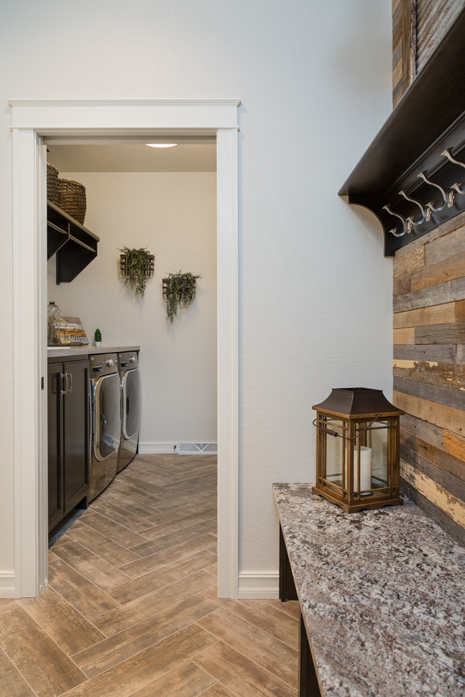 Photo of a mid-sized arts and crafts galley utility room in Other with a drop-in sink, recessed-panel cabinets, dark wood cabinets, granite benchtops, white walls, porcelain floors, a side-by-side washer and dryer and brown floor.