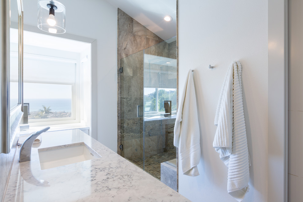 Photo of a mid-sized contemporary master bathroom in Orange County with flat-panel cabinets, white cabinets, a corner shower, a one-piece toilet, gray tile, stone tile, white walls, travertine floors, an undermount sink and engineered quartz benchtops.