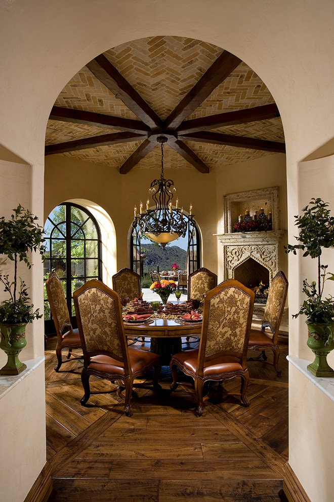 Mediterranean dining room in Other with dark hardwood floors and a standard fireplace.