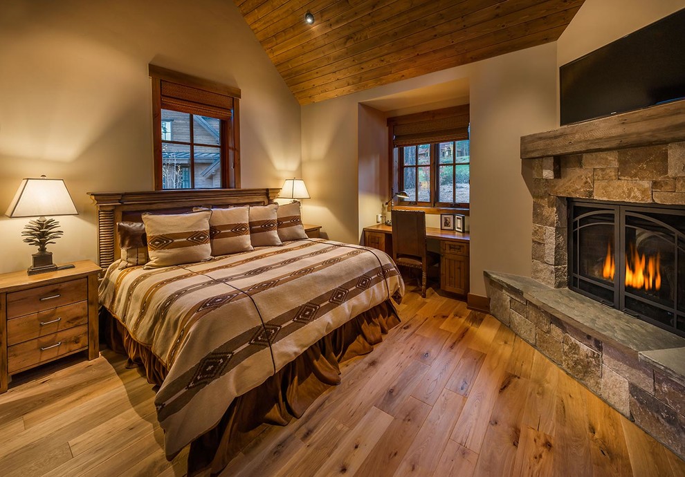 Design ideas for a country bedroom in Sacramento with beige walls, medium hardwood floors, a corner fireplace and a stone fireplace surround.