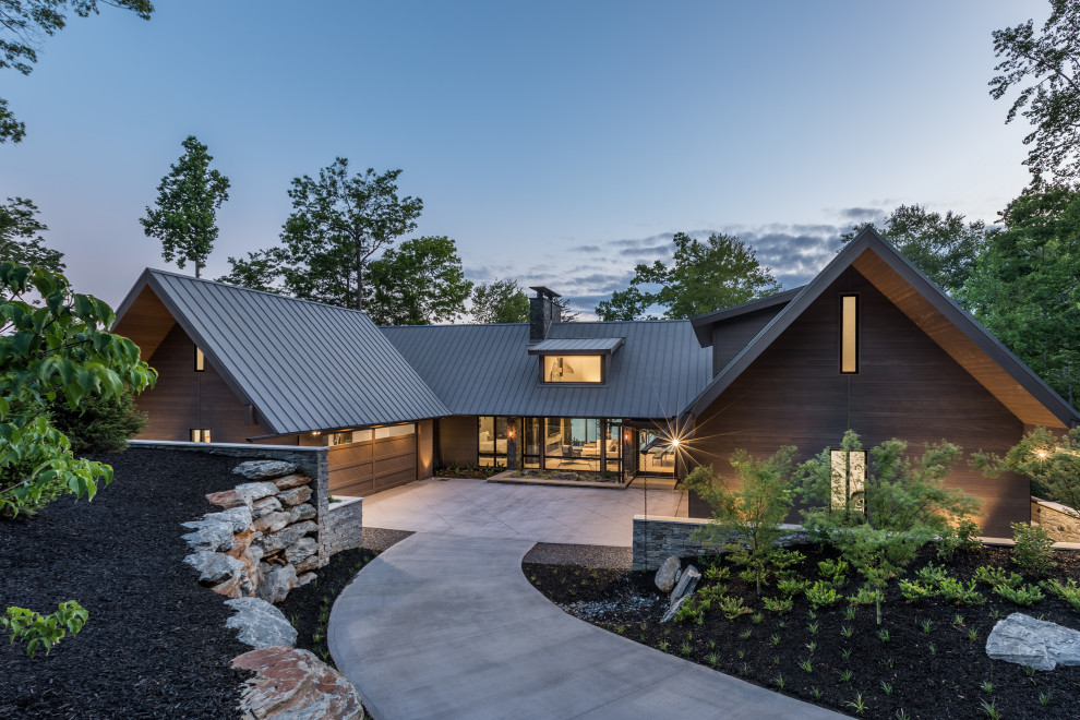 Стильный дизайн: трехэтажный, деревянный, коричневый частный загородный дом среднего размера в современном стиле с двускатной крышей, металлической крышей, отделкой планкеном и черной крышей - последний тренд