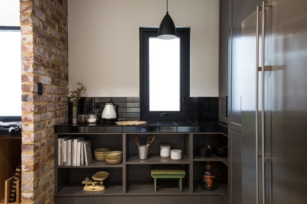 Expansive industrial galley kitchen pantry in Other with a double-bowl sink, shaker cabinets, grey cabinets, solid surface benchtops, black splashback, subway tile splashback, stainless steel appliances, concrete floors, with island, grey floor and white benchtop.