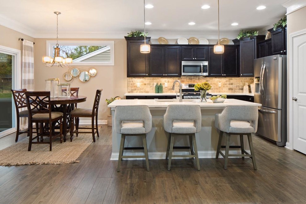 Eat-in kitchen - mid-sized transitional l-shaped dark wood floor and brown floor eat-in kitchen idea in Cincinnati with an undermount sink, recessed-panel cabinets, dark wood cabinets, brown backsplash, ceramic backsplash, stainless steel appliances, an island and white countertops