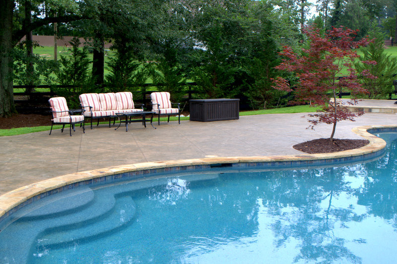 Large traditional backyard custom-shaped pool in Atlanta with a pool house and stamped concrete.