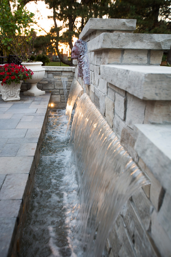 Design ideas for a transitional backyard stone water fountain landscape in Omaha.