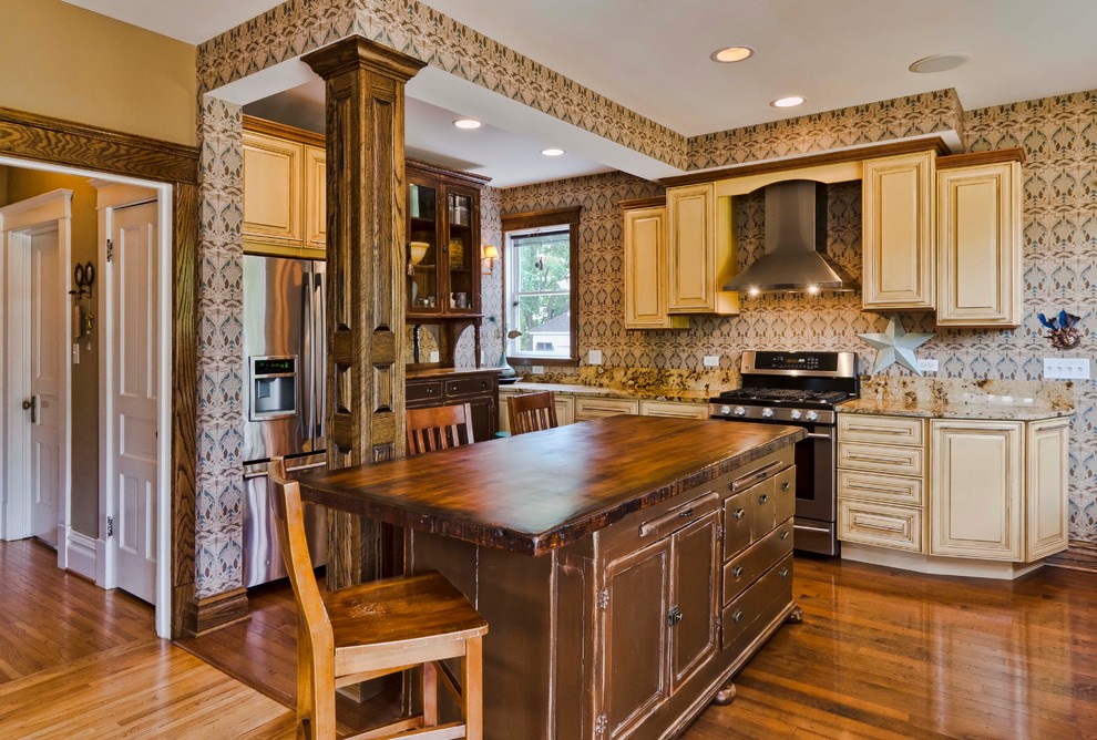 Design ideas for a large traditional l-shaped open plan kitchen in Chicago with an undermount sink, raised-panel cabinets, brown cabinets, granite benchtops, beige splashback, stone slab splashback, stainless steel appliances, medium hardwood floors and with island.