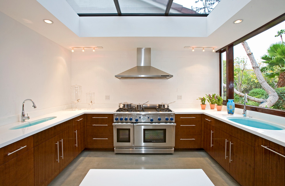 This is an example of a midcentury u-shaped separate kitchen in Los Angeles with an undermount sink, flat-panel cabinets, dark wood cabinets, white splashback and stainless steel appliances.