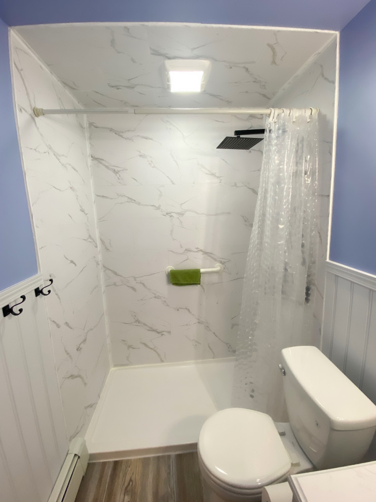 На фото: маленькая ванная комната в стиле кантри с фасадами островного типа, белыми фасадами, открытым душем, раздельным унитазом, серой плиткой, синими стенами, полом из ламината, душевой кабиной, монолитной раковиной, столешницей из искусственного кварца, серым полом, шторкой для ванной, белой столешницей, тумбой под одну раковину, напольной тумбой и панелями на стенах для на участке и в саду с