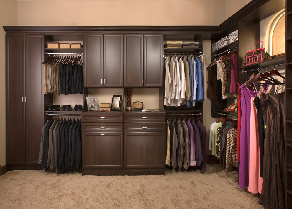 Photo of a mid-sized transitional gender-neutral walk-in wardrobe in Boston with dark wood cabinets, carpet and recessed-panel cabinets.