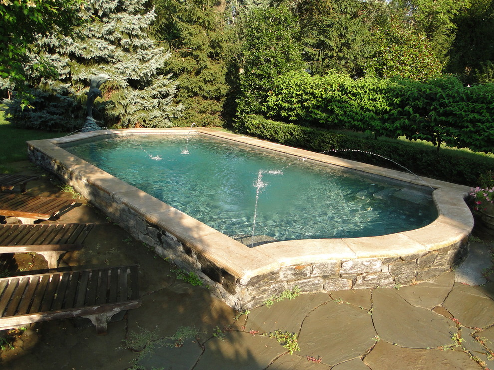 Photo of a small traditional backyard custom-shaped pool in Philadelphia with a water feature and natural stone pavers.