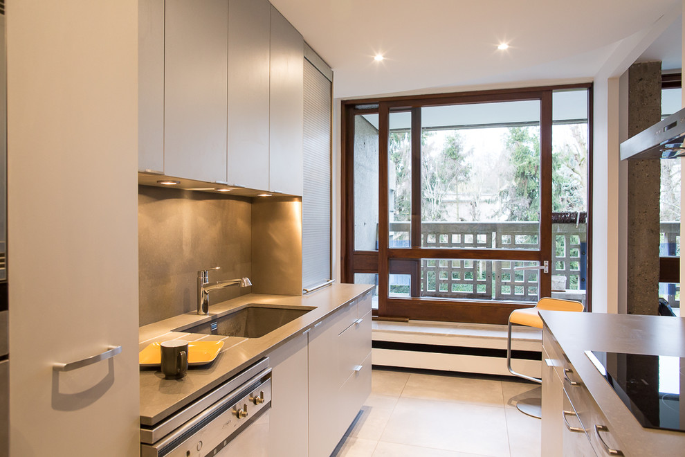 Photo of a contemporary galley kitchen in Paris with an undermount sink, quartzite benchtops, grey splashback, stainless steel appliances, grey benchtop, flat-panel cabinets, beige cabinets and beige floor.