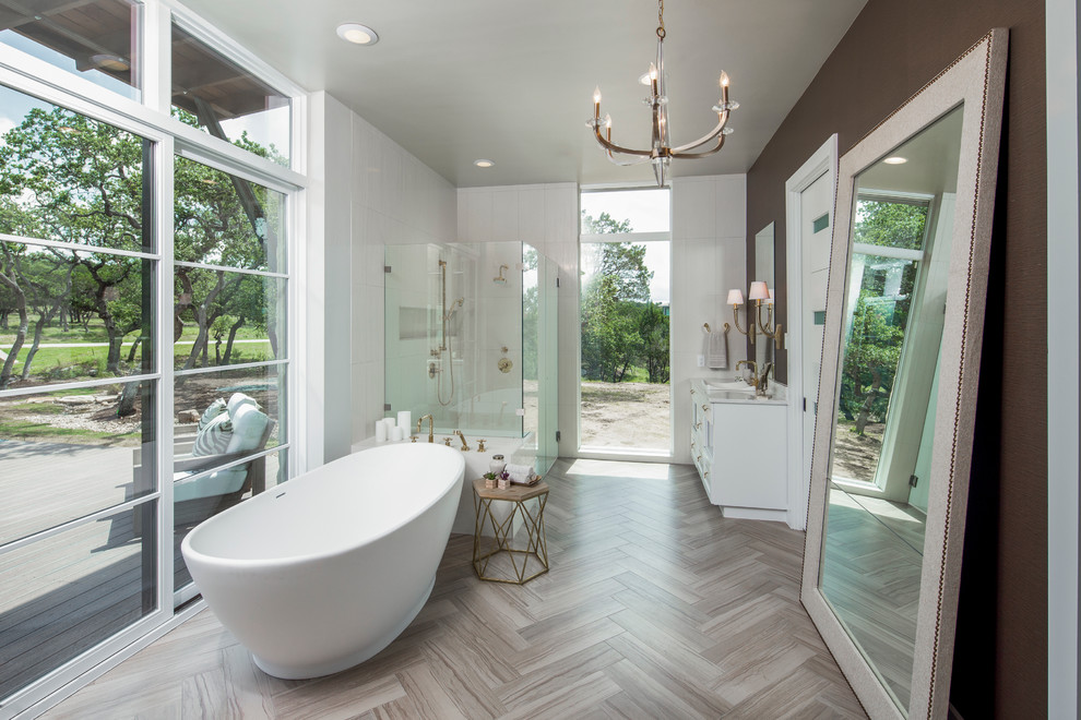 Inspiration for a transitional medium tone wood floor freestanding bathtub remodel in Austin with white cabinets, marble countertops and brown walls