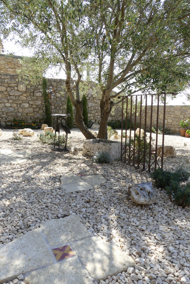 This is an example of a small mediterranean full sun xeriscape in Other with natural stone pavers and with rock feature.