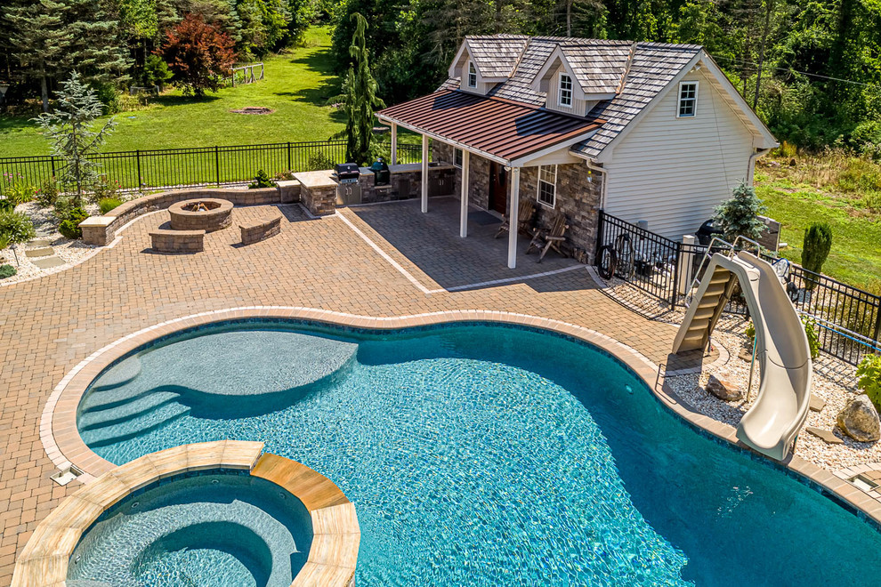 Design ideas for a large traditional backyard custom-shaped pool in Philadelphia with a pool house and concrete pavers.
