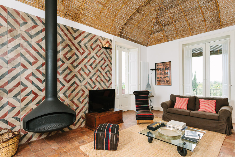 Inspiration for a large eclectic enclosed living room in Catania-Palermo with multi-coloured walls, a hanging fireplace, a freestanding tv, terra-cotta floors and a metal fireplace surround.