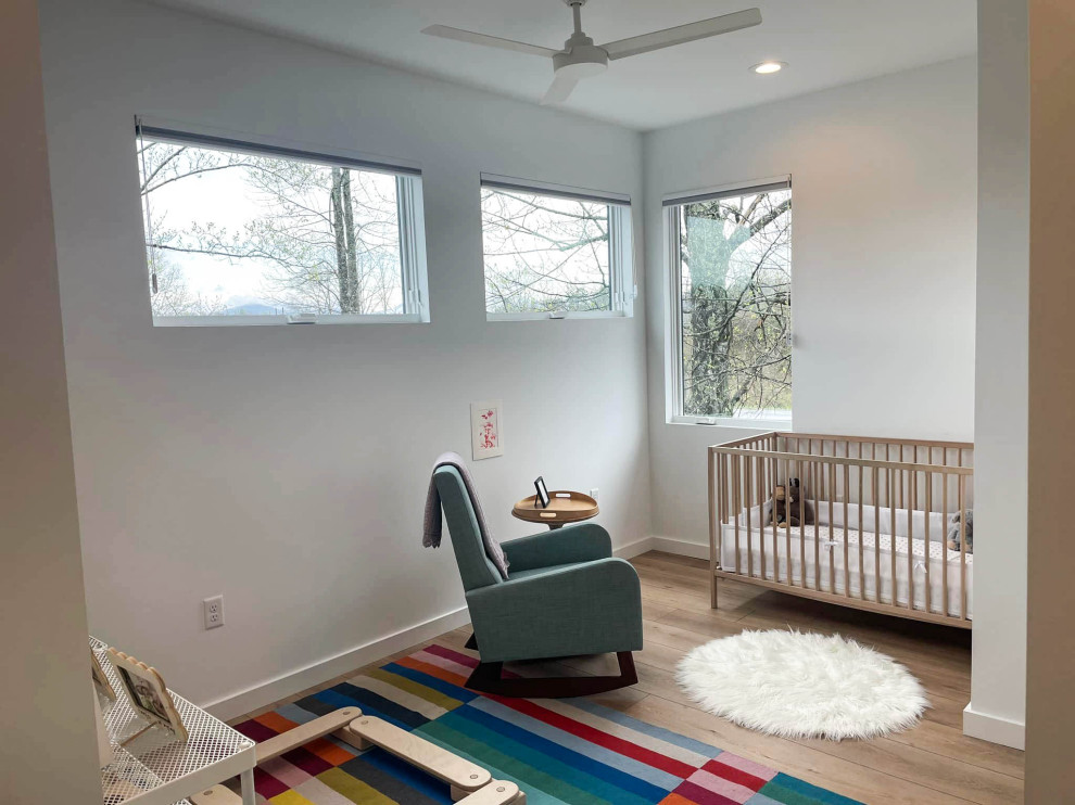 Modelo de habitación de bebé neutra blanca moderna de tamaño medio con paredes blancas, suelo vinílico y suelo multicolor