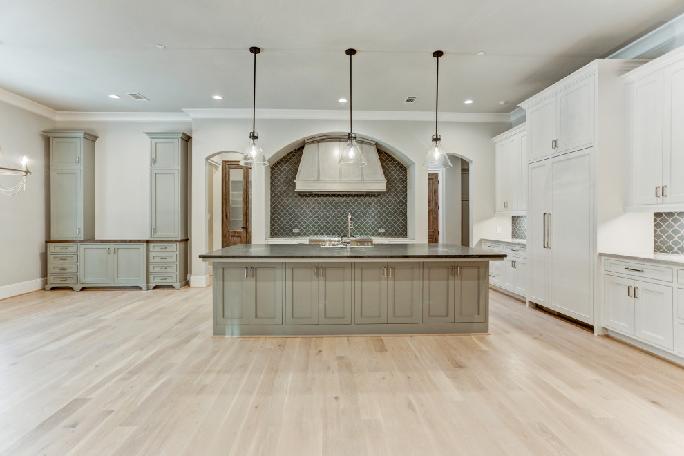 Inspiration for a large l-shaped open plan kitchen in Houston with a farmhouse sink, recessed-panel cabinets, white cabinets, mosaic tile splashback, stainless steel appliances, light hardwood floors, with island, beige floor and brown benchtop.