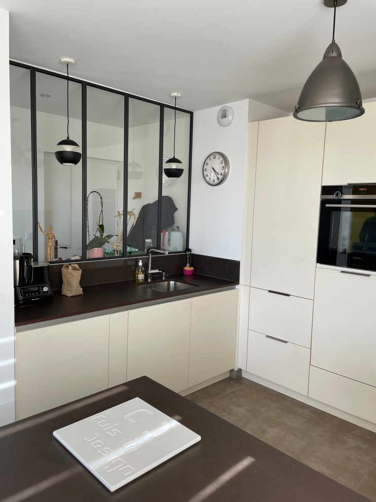 Exempel på ett mellanstort modernt brun brunt kök, med en integrerad diskho, luckor med profilerade fronter, skåp i rostfritt stål, bänkskiva i kvartsit, svart stänkskydd, stänkskydd i glaskakel, färgglada vitvaror, cementgolv, en köksö och grått golv