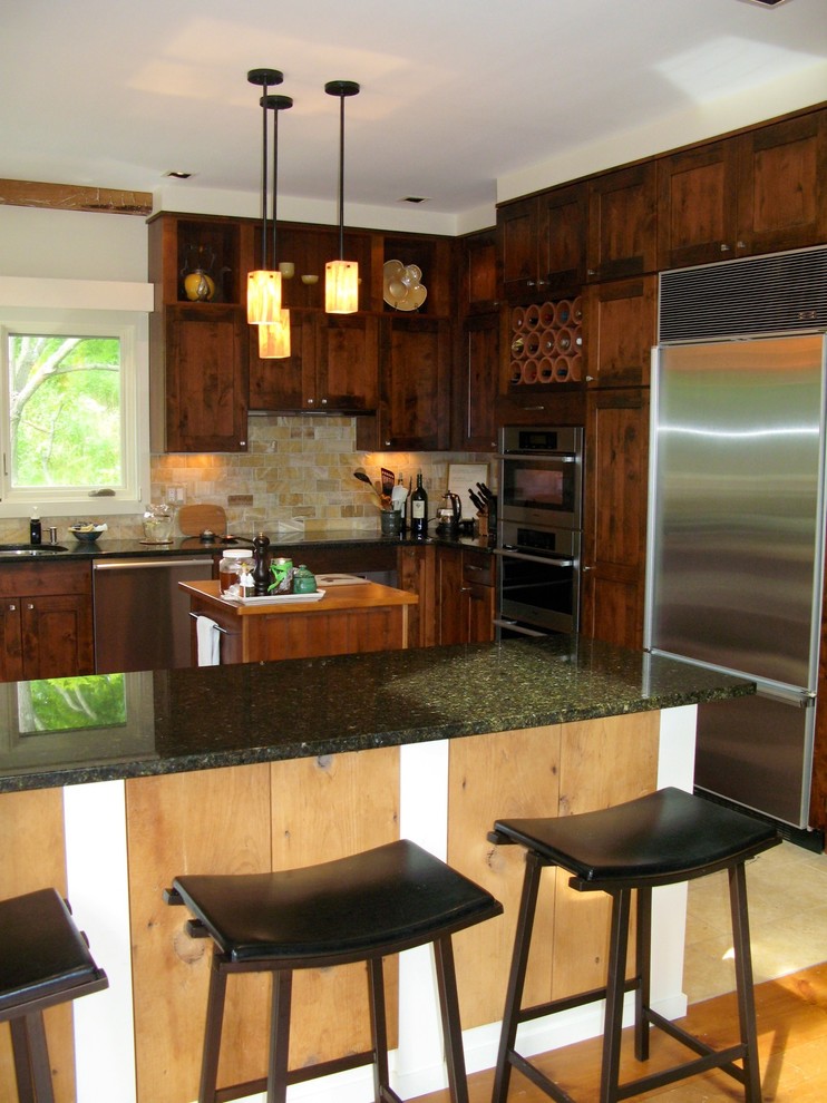 Mid-sized mountain style u-shaped limestone floor, beige floor and exposed beam eat-in kitchen photo with an undermount sink, shaker cabinets, medium tone wood cabinets, glass countertops, beige backsplash, stone tile backsplash, stainless steel appliances, an island and black countertops
