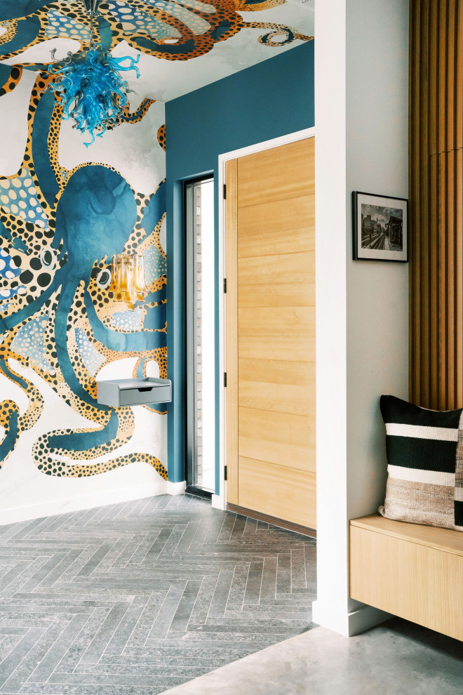 Idée de décoration pour une entrée design de taille moyenne avec un vestiaire, un mur multicolore, sol en béton ciré, une porte simple, une porte en bois clair et un sol gris.