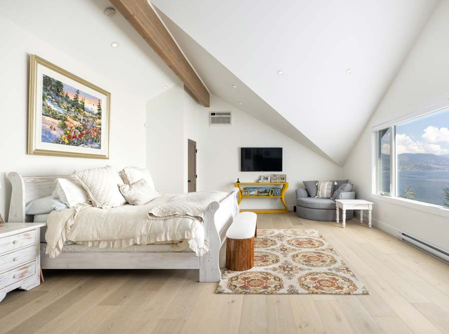 Inspiration for a large country master bedroom in Vancouver with white walls, light hardwood floors, brown floor and vaulted.