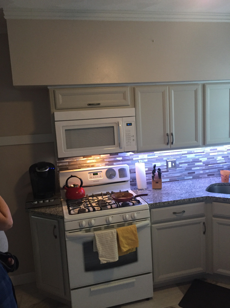 Example of a mid-sized transitional l-shaped ceramic tile and gray floor kitchen design in St Louis with an undermount sink, recessed-panel cabinets, gray cabinets, granite countertops, multicolored backsplash, glass sheet backsplash, white appliances and multicolored countertops