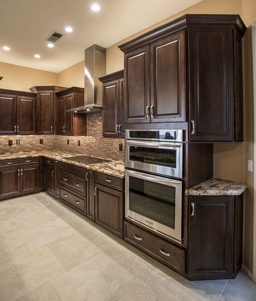 Example of a mid-sized transitional l-shaped ceramic tile open concept kitchen design in Phoenix with an undermount sink, raised-panel cabinets, dark wood cabinets, granite countertops, brown backsplash, glass tile backsplash, stainless steel appliances and an island