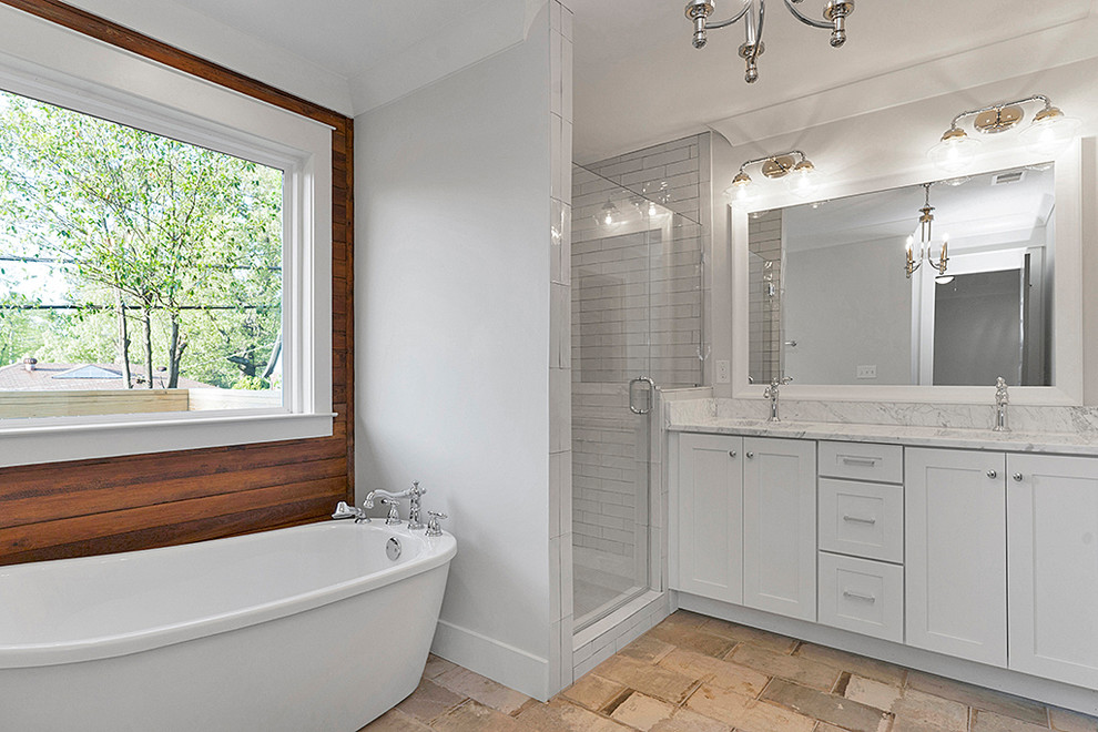 Inspiration for a mid-sized transitional master bathroom in Birmingham with shaker cabinets, white cabinets, a freestanding tub, an alcove shower, white tile, subway tile, grey walls, an undermount sink, marble benchtops, beige floor, a hinged shower door and grey benchtops.