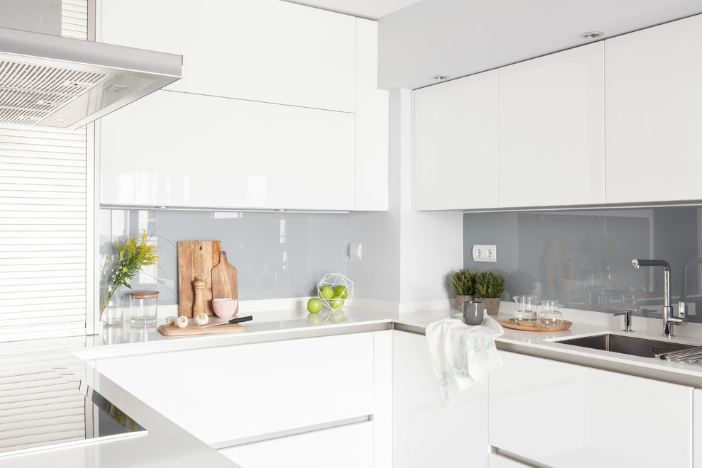 Design ideas for a mid-sized modern u-shaped open plan kitchen in Madrid with an undermount sink, flat-panel cabinets, white cabinets, laminate benchtops, grey splashback, window splashback, stainless steel appliances, laminate floors, a peninsula, grey floor and white benchtop.