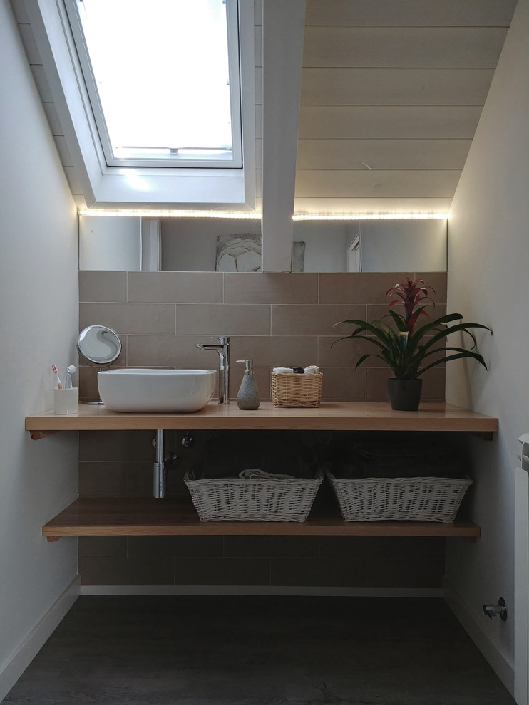 Modelo de aseo contemporáneo con baldosas y/o azulejos grises, baldosas y/o azulejos de cerámica, paredes blancas, lavabo sobreencimera, encimera de madera y suelo gris