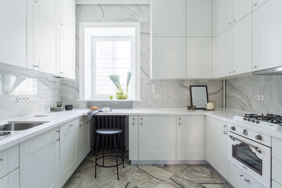 Inspiration for a transitional u-shaped kitchen in Moscow with a drop-in sink, shaker cabinets, white cabinets, white appliances, no island, white benchtop, white splashback, marble splashback and multi-coloured floor.