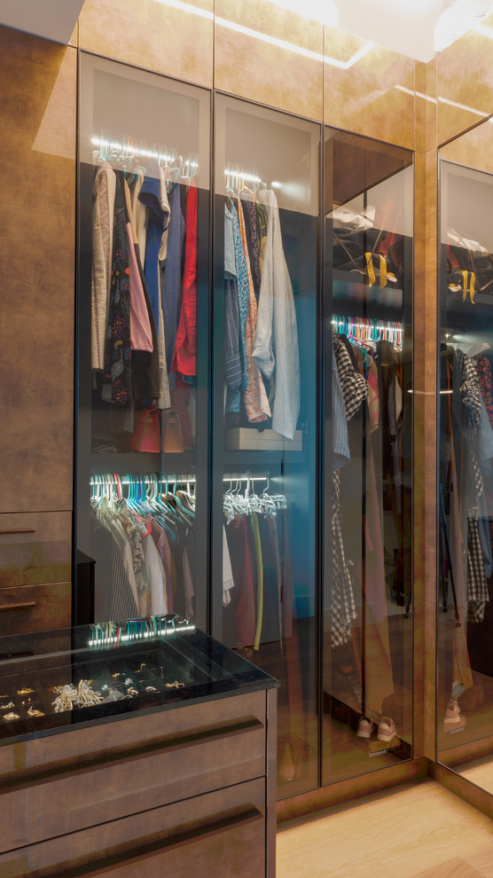 Inspiration for a large modern gender-neutral walk-in wardrobe in Miami with glass-front cabinets and brown cabinets.