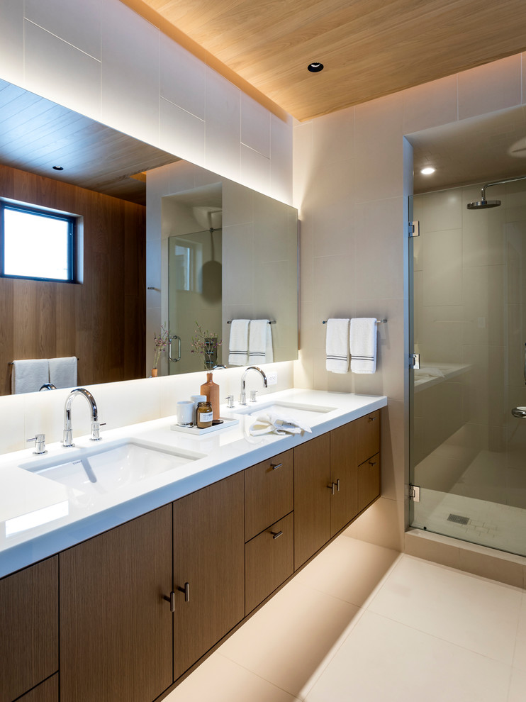 Large contemporary 3/4 bathroom in Denver with flat-panel cabinets, a freestanding tub, a corner shower, a wall-mount toilet, beige tile, stone slab, an undermount sink, glass benchtops, white floor, a hinged shower door, white walls and porcelain floors.